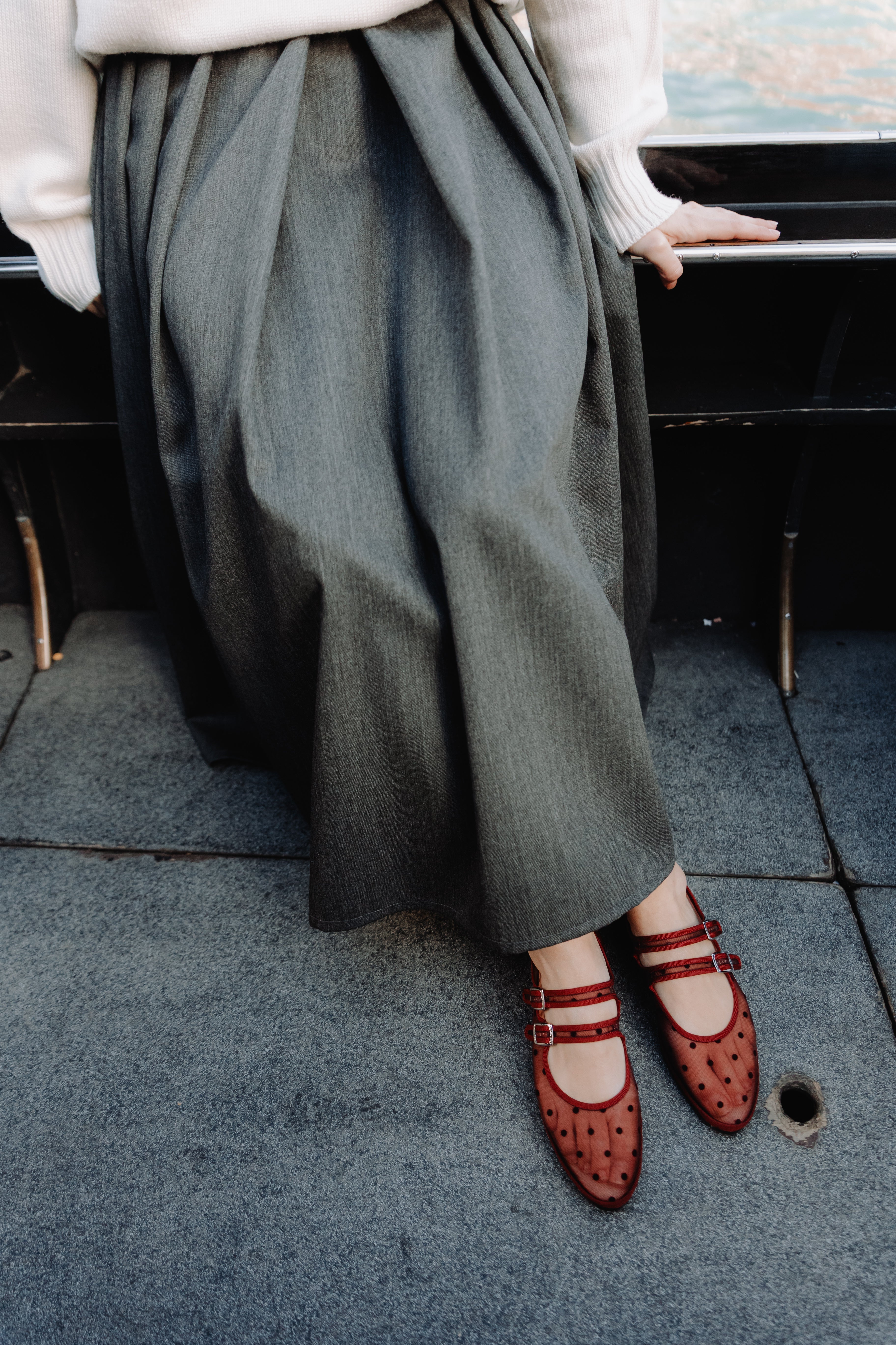 Person wearing green wide-leg pants and red shoes on a city street.